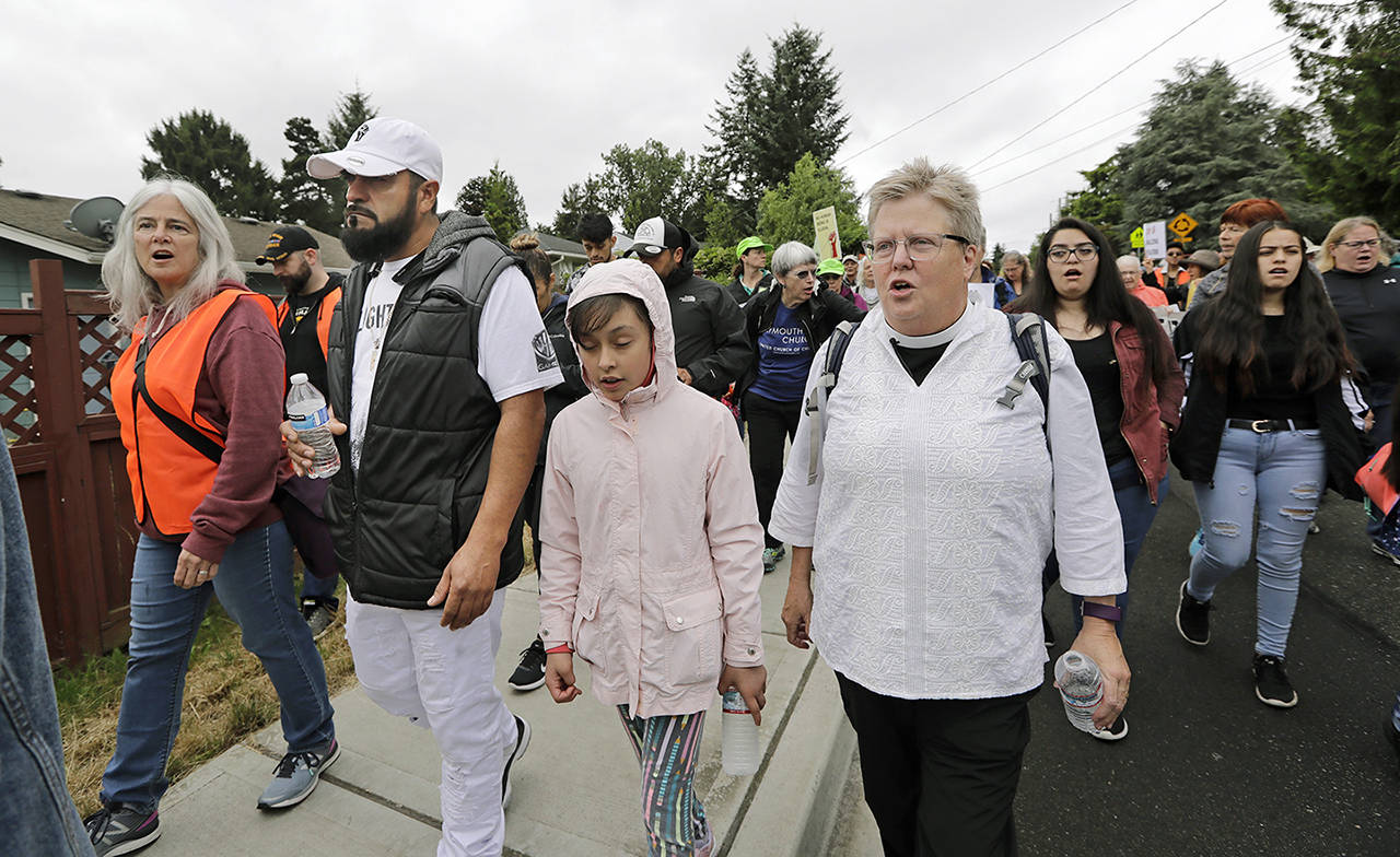 In this July 17 photo, Jose Robles (second left) walks with Gethsemane Lutheran Church Pastor Joanne Engquist (right) and hundreds of supports as Robles walks to present himself to himself U.S. Immigration and Customs Enforcement officials in Tukwila. (AP Photo/Elaine Thompson, file)