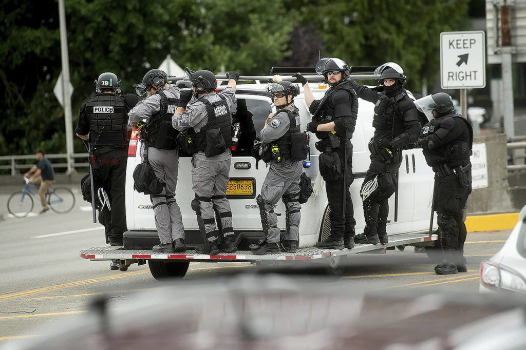 Police officers ride on the side of a van as right-wing demonstrators and counter-protesters gather in Portland for an “End Domestic Terrorism” rally on Saturday. Police seized metal poles, bear spray and other weapons as hundreds of far-right protesters and anti-fascist counter-demonstrators swarmed downtown Portland. (AP Photo/Noah Berger)

