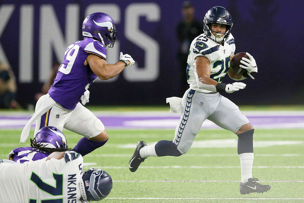 Seattle’s Travis Homer (25) runs away from Minnesota’s Marcus Epps (left) during Sunday’s preseason game in Minneapolis. (AP Photo/Jim Mone)