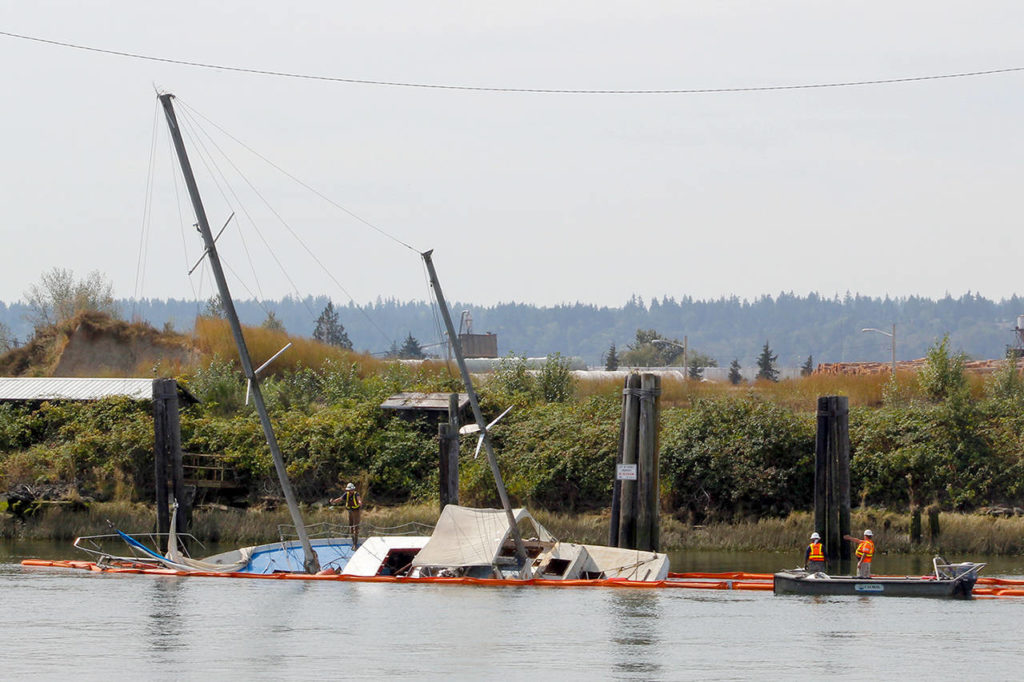 Contractors for the state Department of Ecology investigate a sunken sailboat Tuesday morning on the Snohomish River. (Joey Thompson / The Herald)
