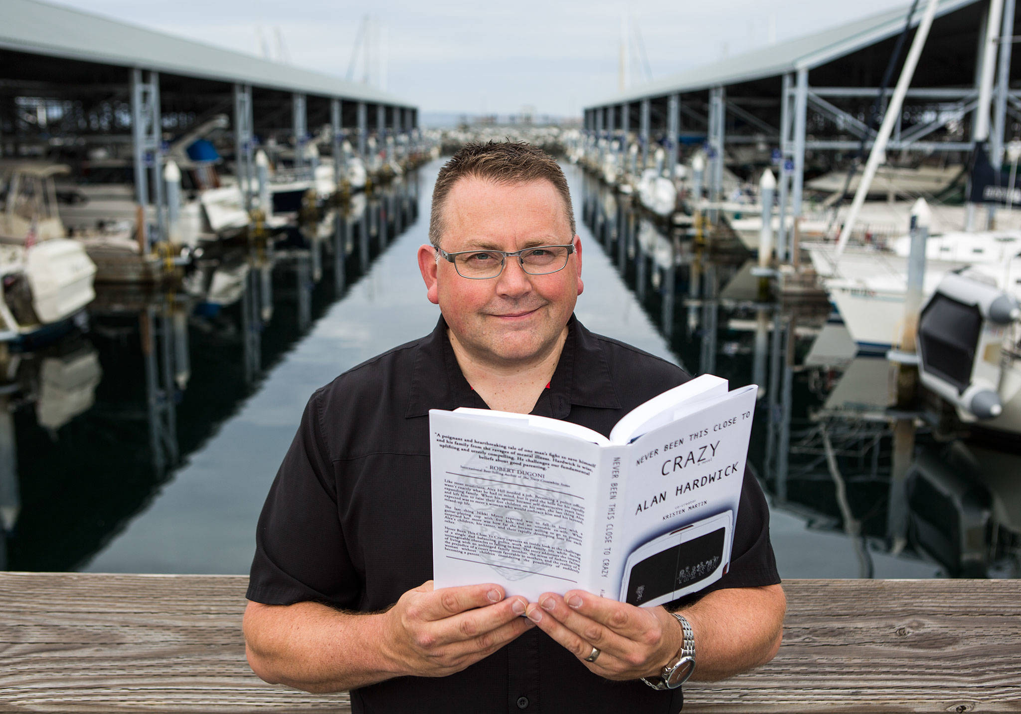 Alan Hardwick, author of “Never Been This Close To Crazy,” in Edmonds next to the marina where he keeps his boat, “PostMate,” named after a scene in his book. (Olivia Vanni / The Herald)
