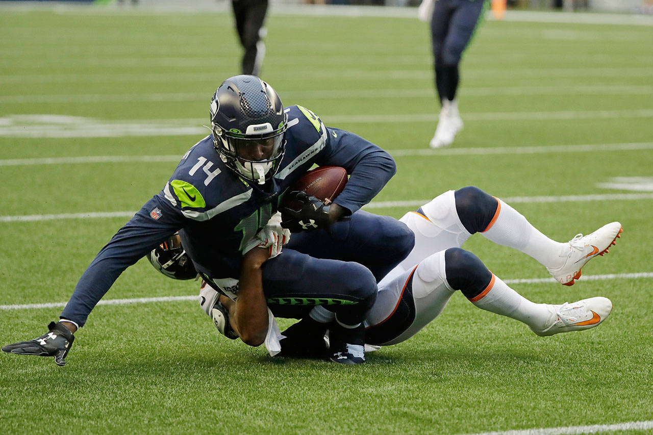 Seahawks wide receiver DK Metcalf (14) is tackled by Broncos cornerback Chris Harris after making a catch during the first half of a preseason game on Aug. 8, 2019, in Seattle. (AP Photo/Elaine Thompson)