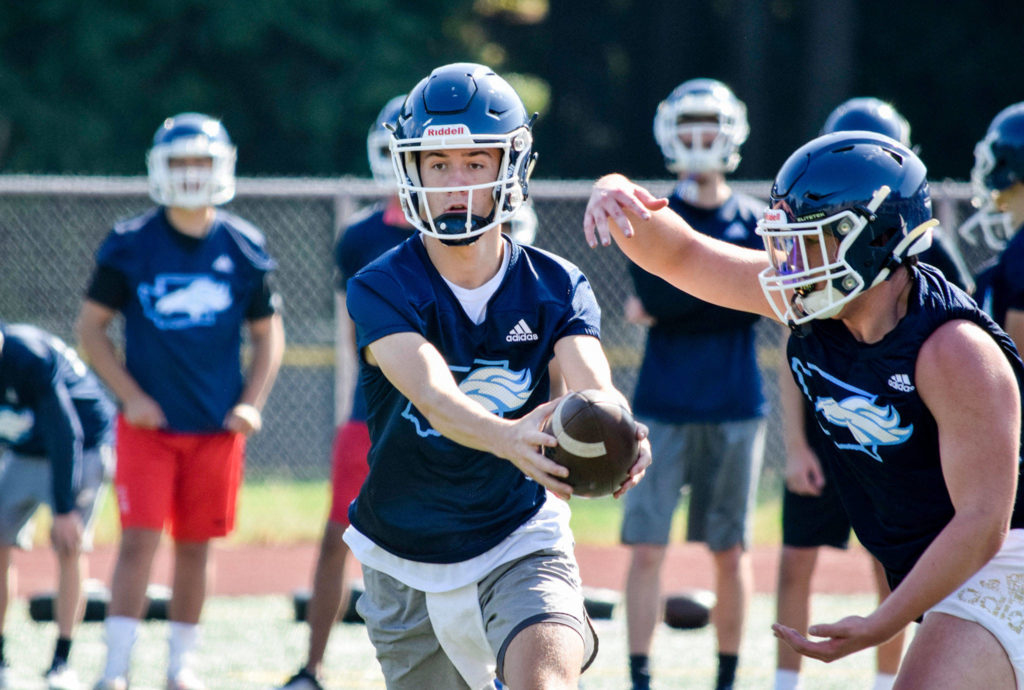 Senior quarterback Hunter Moen hands-off the ball to junior running back Ian Newsom at Meadowdale High School on Thursday, Aug. 22. (Katie Webber / The Herald)
