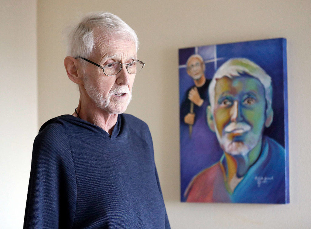 About a month before his death, Robert Fuller stands near a portrait of himself, done before he became ill, at his home in Seattle. (AP Photo/Elaine Thompson)
