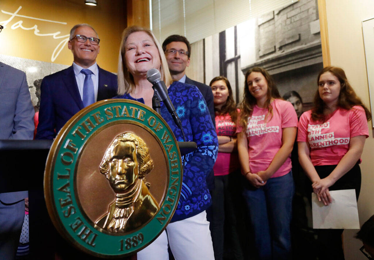 Chris Charbonneau, chief executive for Planned Parenthood of the Great Northwest and the Hawaiian Islands, speaks at a news conference addressing a change in rules on the nearly 50-year-old Title X family planning program as Gov. Jay Inslee (left) and state Attorney General Bob Ferguson look on, Thursday in Seattle. (Elaine Thompson / Associated Press)