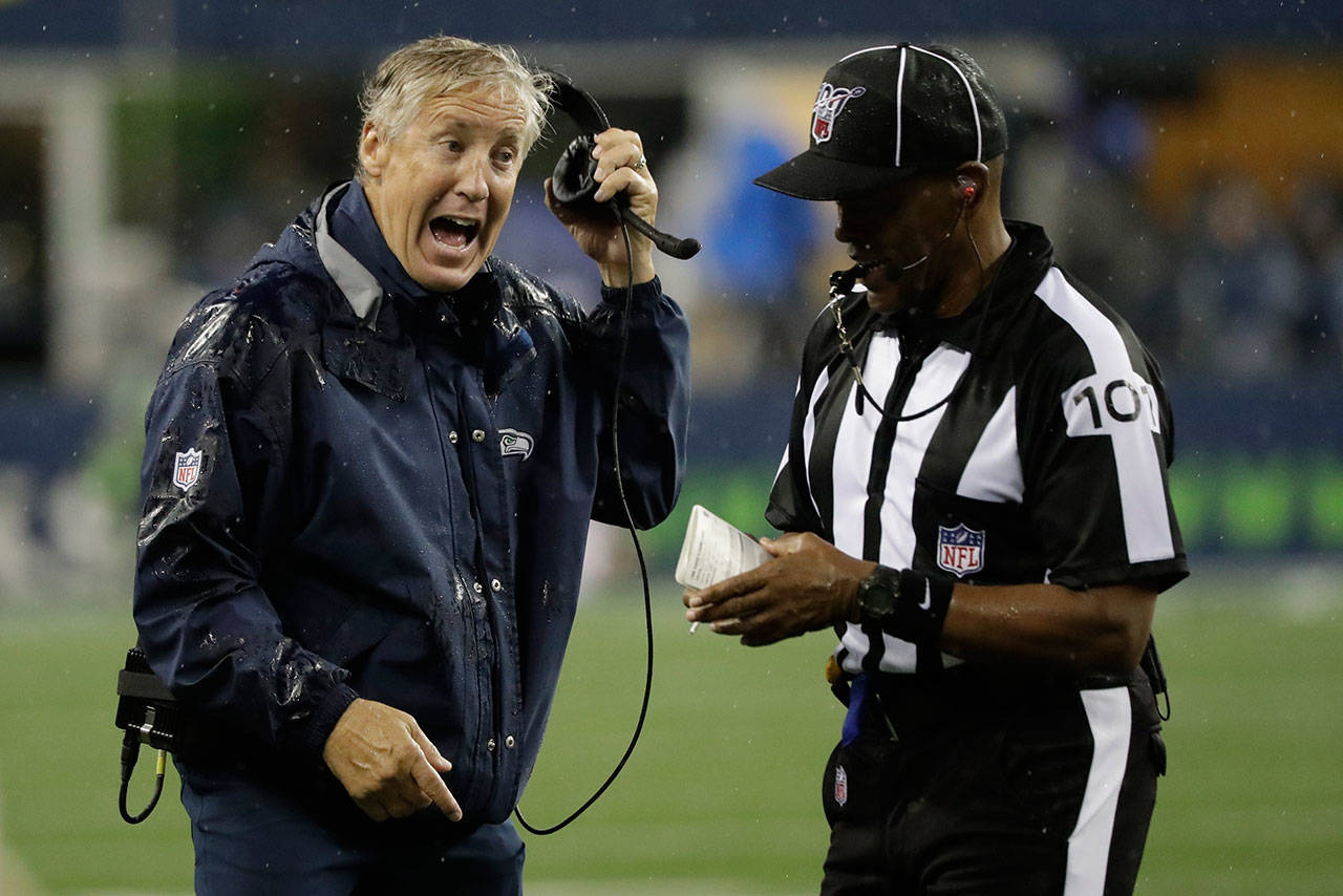 Seahawks head coach Pete Carroll (left) talks with line judge Carl Johnson during the first half of a preseason game against the Raiders on Aug. 29, 2019, in Seattle. (AP Photo/Elaine Thompson)