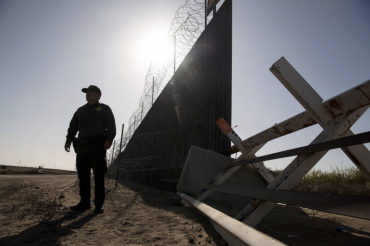 A U.S. Border Patrol agent stands Aug. 23 in Calexico, California, next to a stretch of fence on the U.S.-Mexico border that is to be replaced. (Carolyn Van Houten/Washington Post)