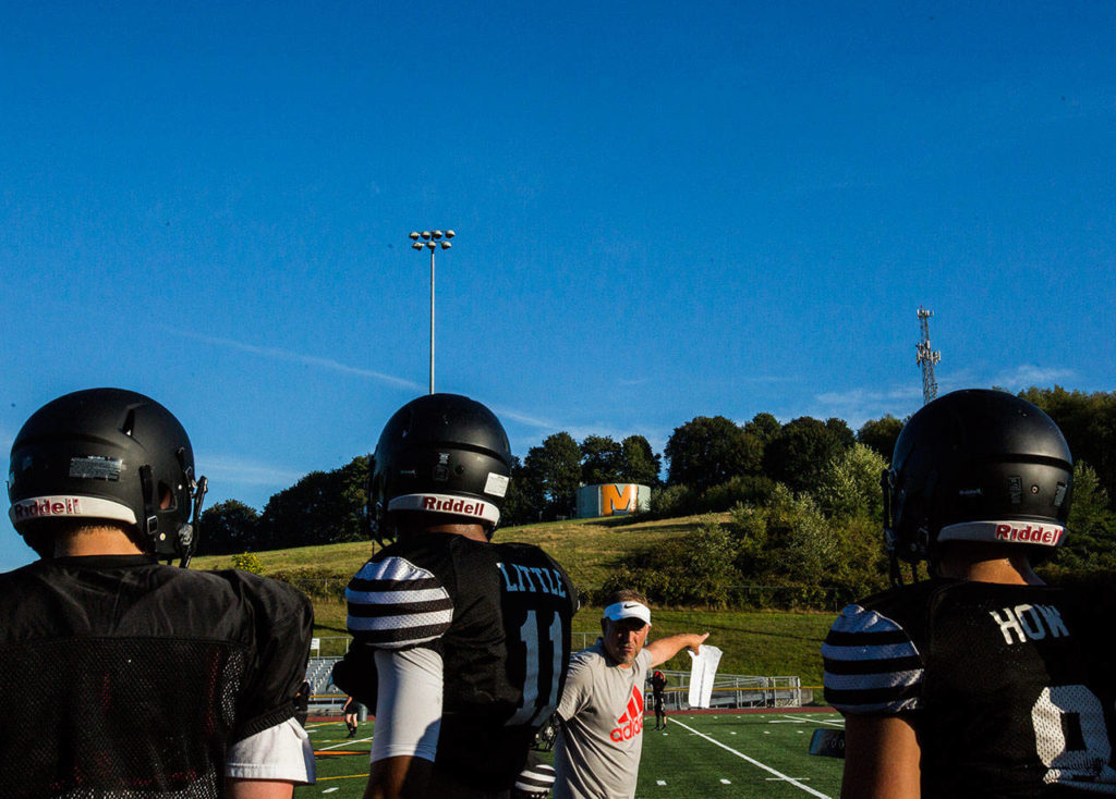 Players listen to plays calls from the sidelines during football practice at Monroe High School on Wednesday, Aug. 28, 2019 in Monroe, Wash. (Olivia Vanni / The Herald)
