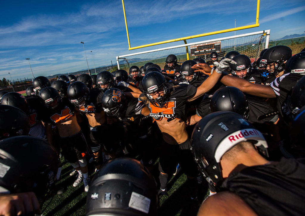 The Monroe High School football team gets together in a huddle before the start of football practice on Wednesday, Aug. 28, 2019 in Monroe, Wash. (Olivia Vanni / The Herald)
