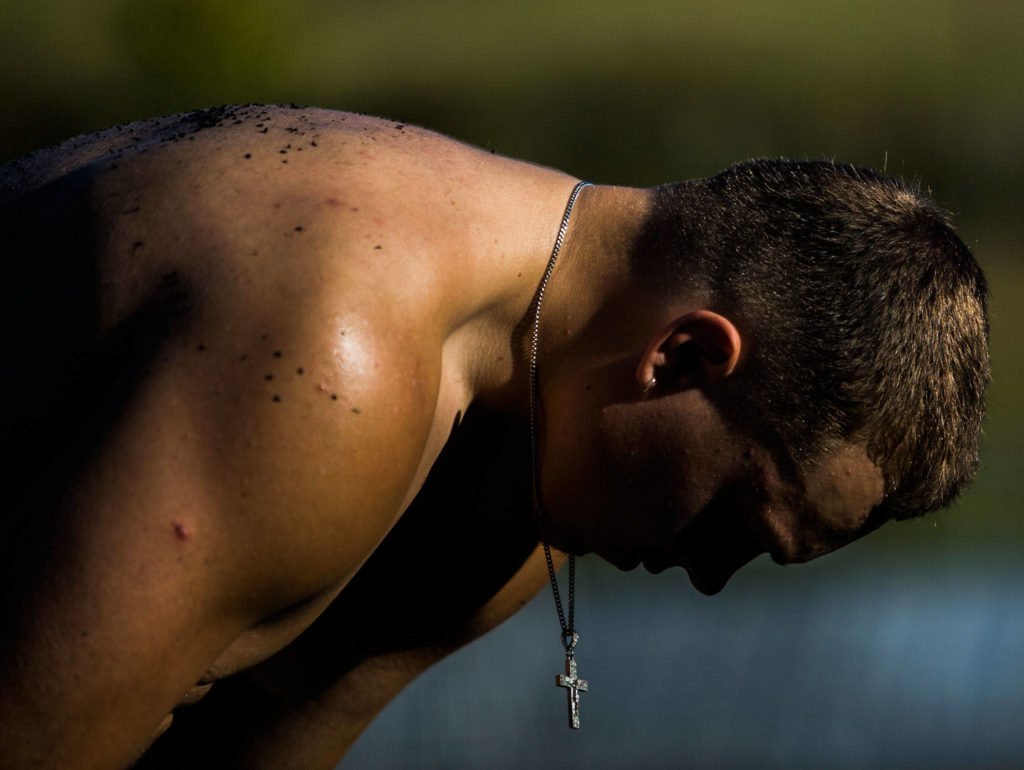 Gavin Monroe’s cross hangs as he stretches on the sidelines during football practice at Monroe High School on Wednesday, Aug. 28, 2019 in Monroe, Wash. (Olivia Vanni / The Herald)
