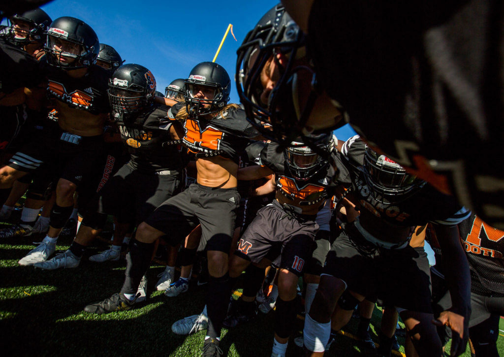 The Monroe High School football team gets together in a huddle before the start of football practice on Wednesday, Aug. 28, 2019 in Monroe, Wash. (Olivia Vanni / The Herald)
