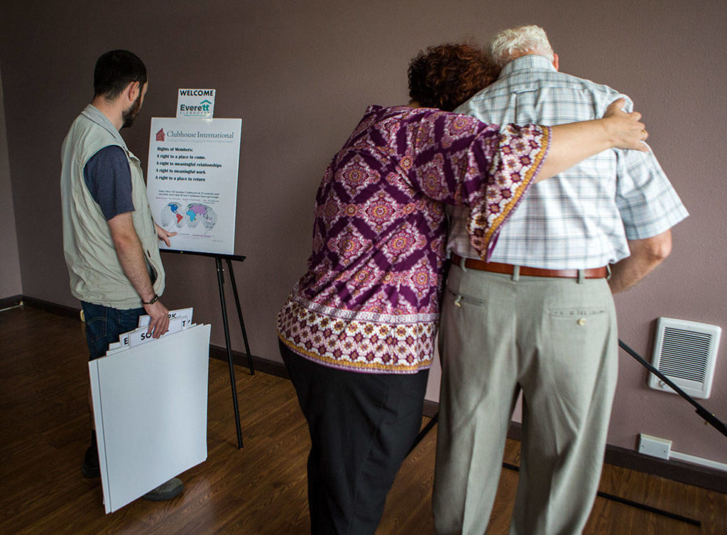 Clubhouse program director Soozee McNamara hugs Harold McClure as they set up poster boards at the new Everett Clubhouse. The McClures worked for more than two years to open the clubhouse, which provides rehabilitation for people living with mental illness. (Olivia Vanni / The Herald)
