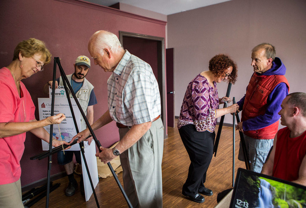 Clubhouse members Alex Odesskiy, Kaid Skirling and Chuck Johnson help set up poster board stands at the new Everett Clubhouse. (Olivia Vanni / The Herald)
