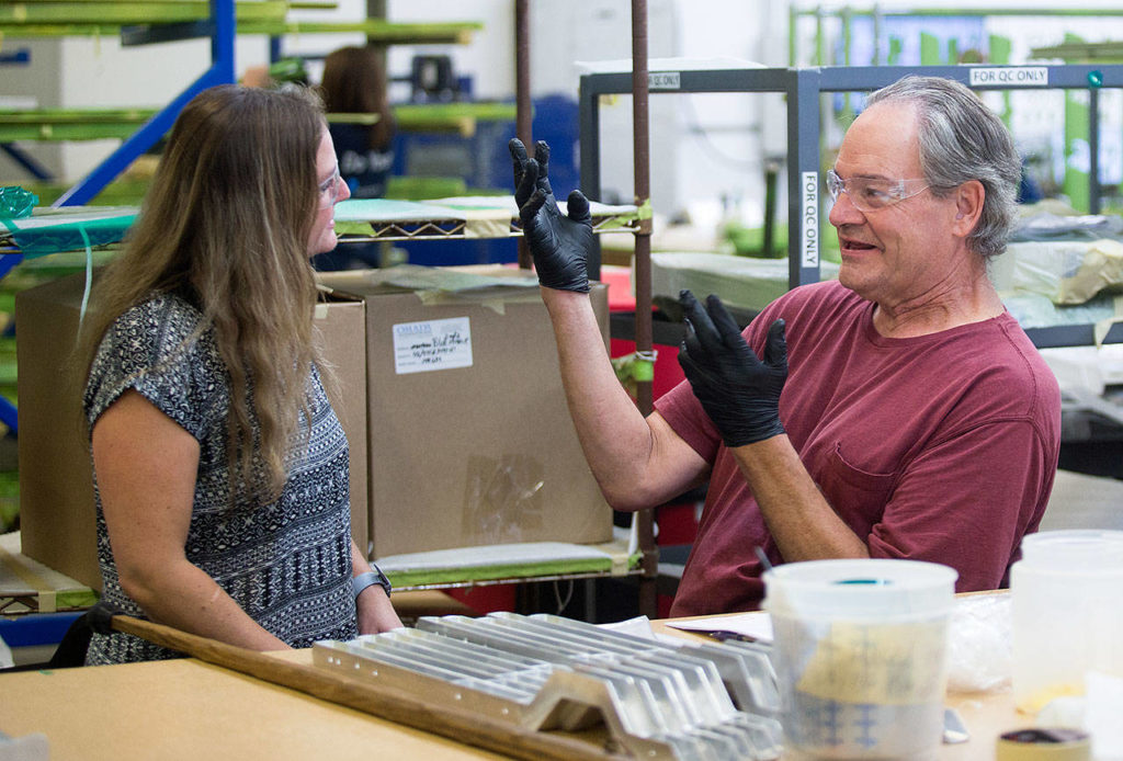 Using signs and a bit of lip-reading, masker Brian Jensen communicates with masking supervisor Patsy Caban at Valence Surface Technologies in Everett. (Andy Bronson / The Herald)
