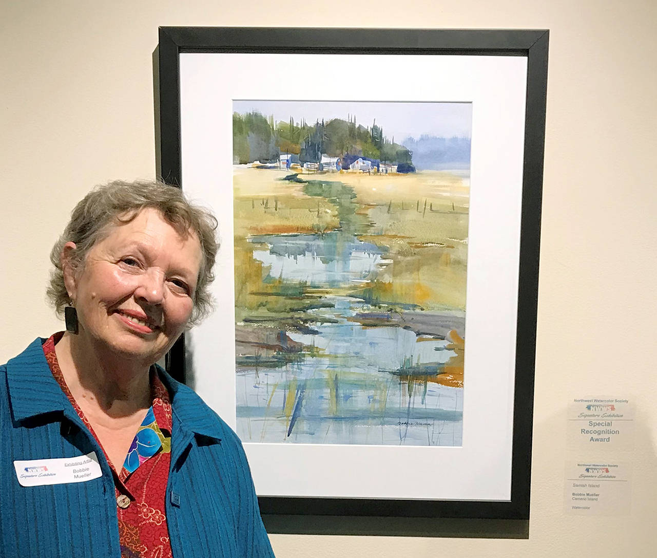 Bobbie Mueller, of Camano Island, poses with one of her watercolor paintings, which are at the Washington State Convention Center through Oct. 6.