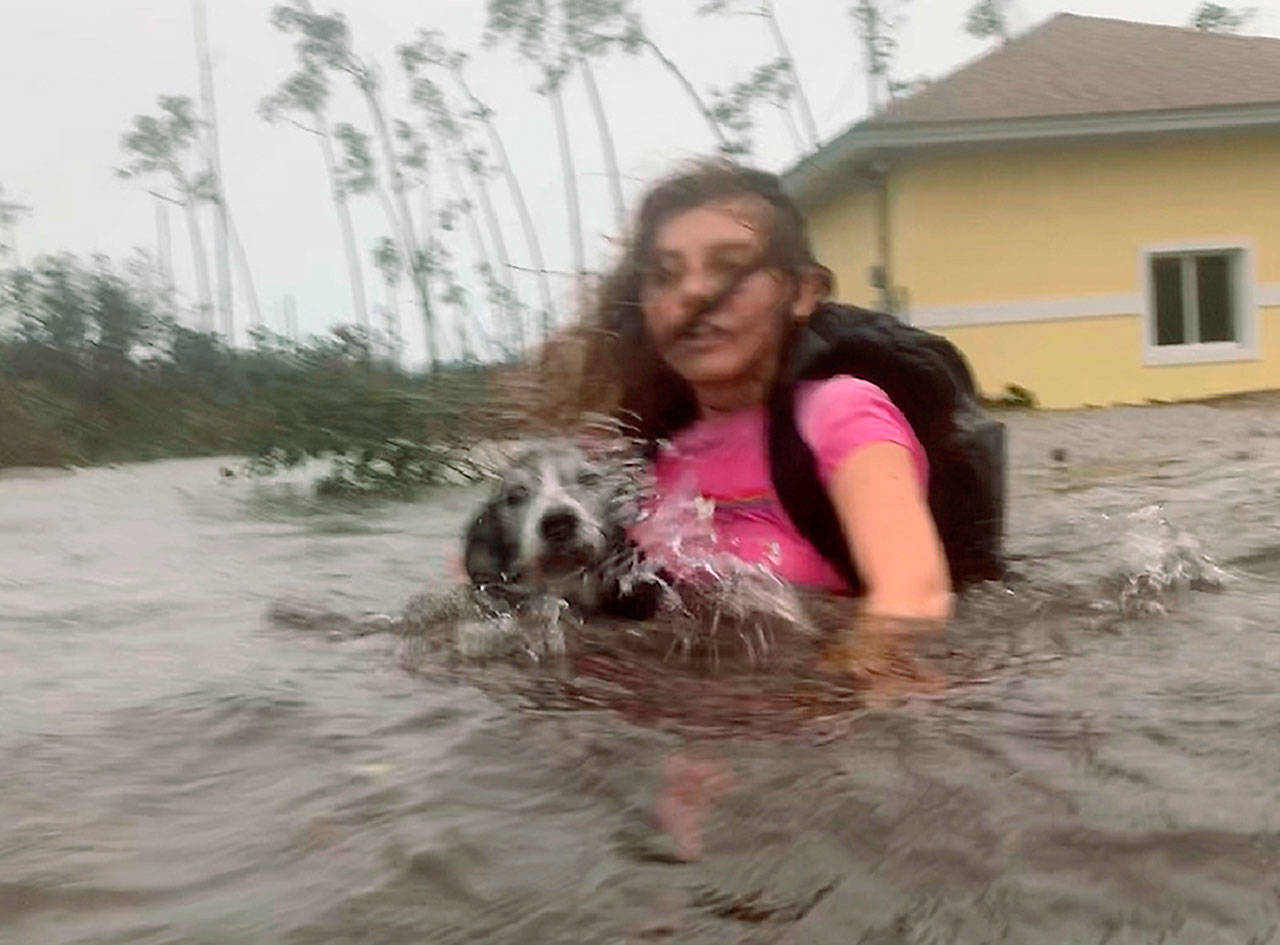 Julia Aylen wades through waist-deep water carrying her dog as she is rescued from her flooded home during Hurricane Dorian in Freeport, Bahamas, on Tuesday. (AP Photo/Tim Aylen)