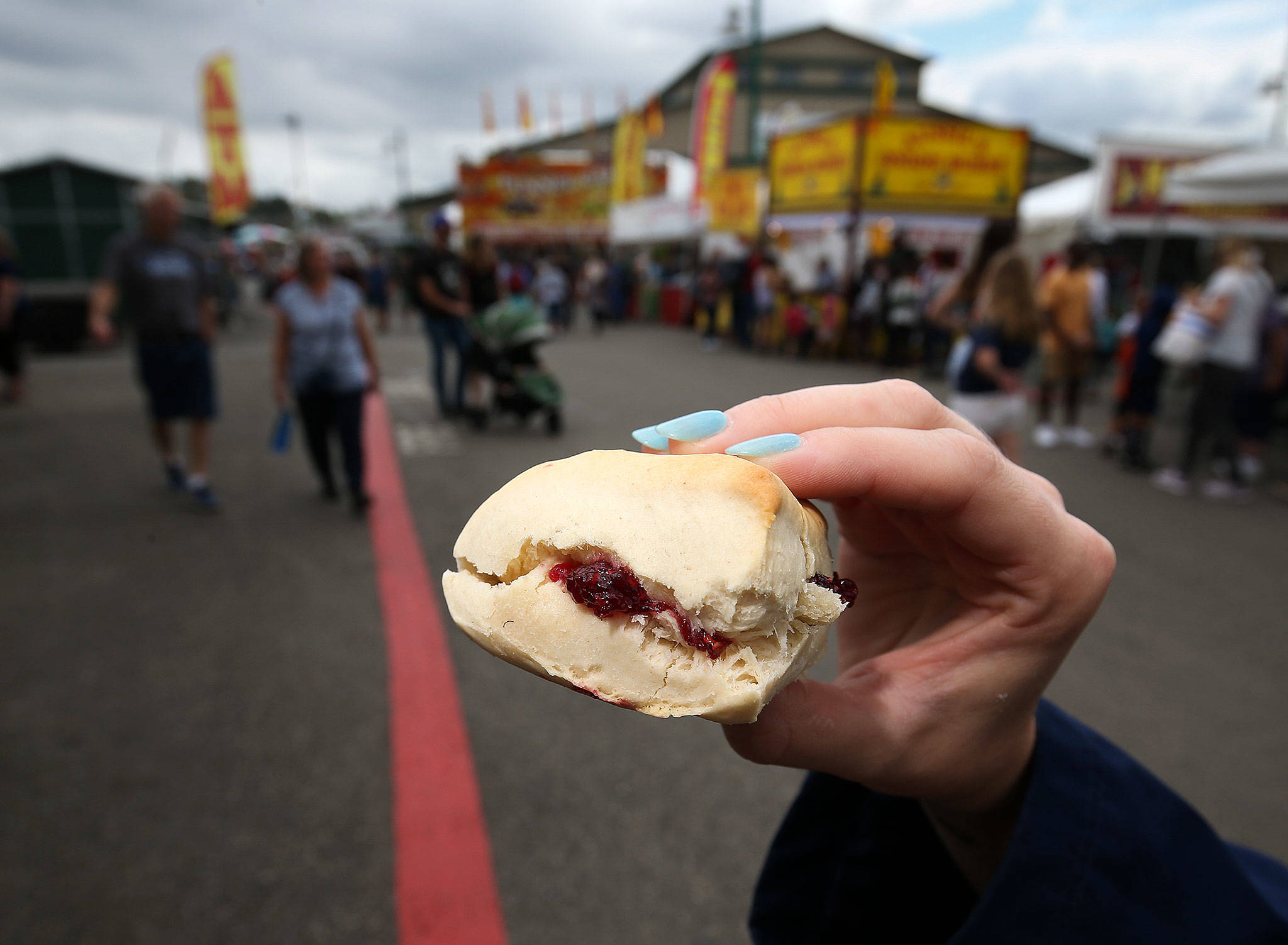 A fairgoer gets ready to bite into a Fisher Fair Scone on opening day of the Evergreen State Fair on Aug. 22. (Andy Bronson / The Herald)