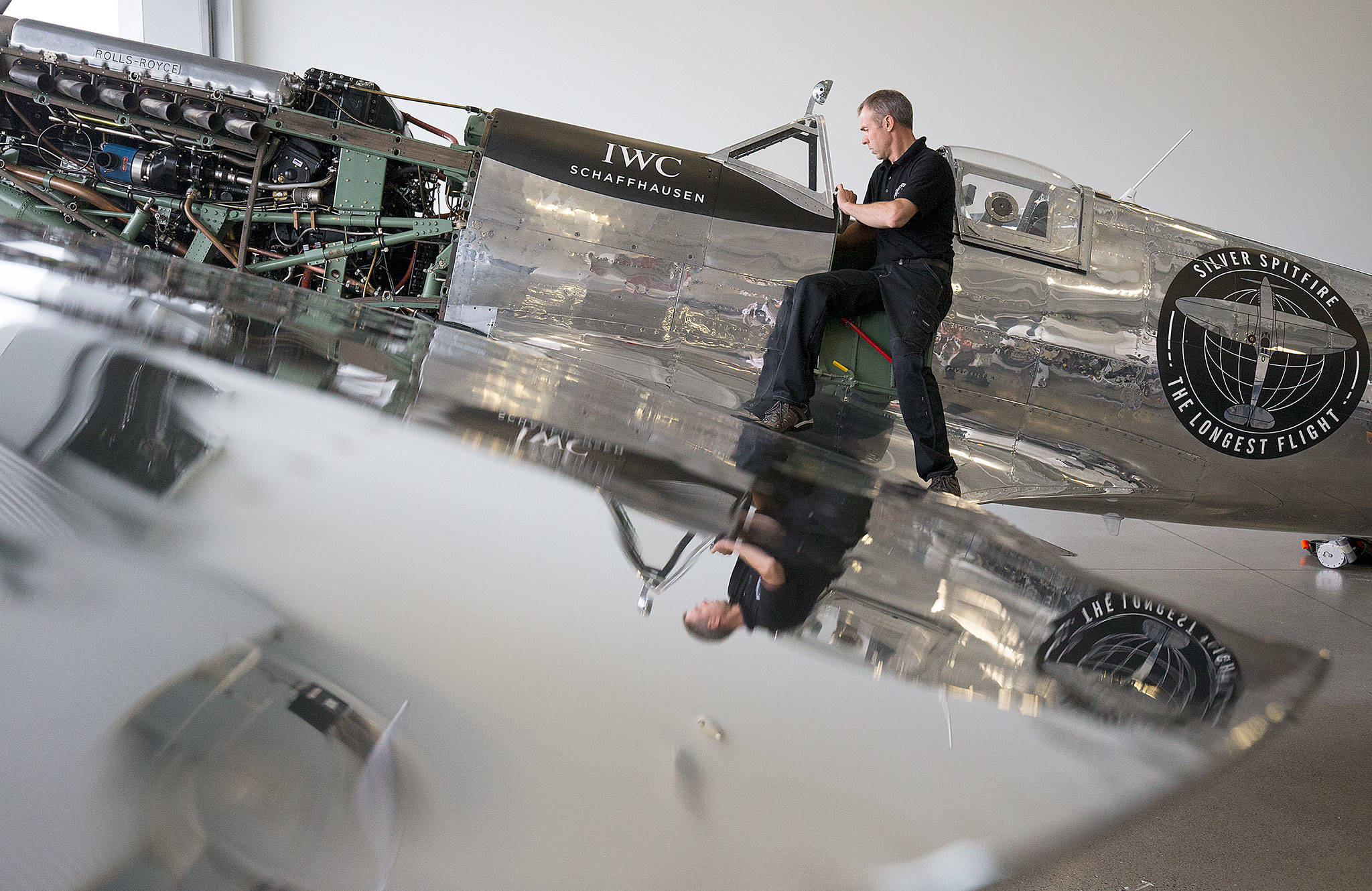 Reflected in the polished aluminum wing, Chief Engineer Martin Overall reaches into the cockpit of the Silver Spitfire, a World War II Supermarine Spitfire Mk.IX fighter plane, during a 50-hour maintenance checkup at the Historic Flight Foundation on Wednesday in Mukilteo. (Andy Bronson / The Herald)