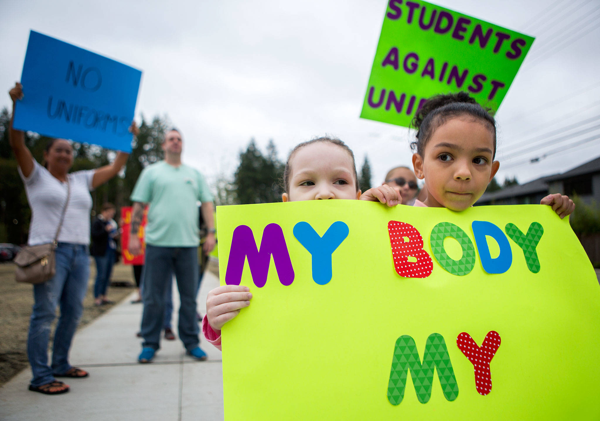 Chloe Savas, 6, right, and sister Kaylee Savas, 3, stand in front of the new Tambark Creek Elementary School on Wednsday, in protest of the uniform policy. (Olivia Vanni / The Herald)