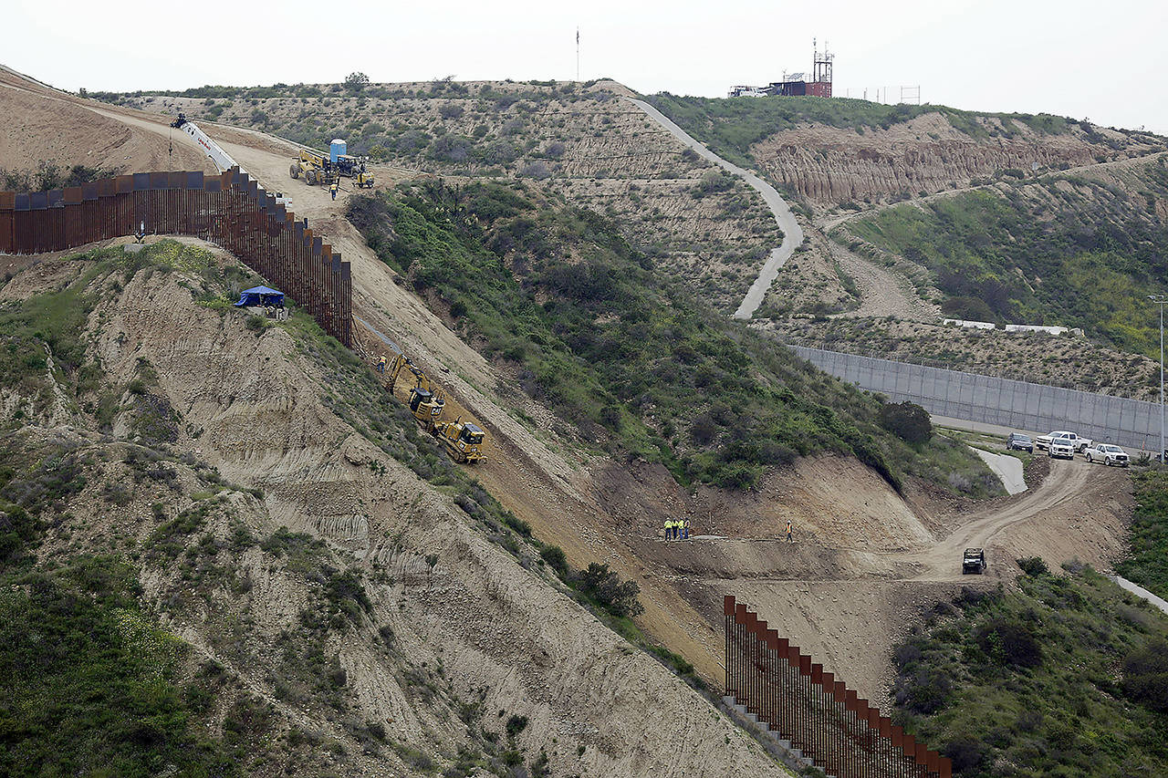 In this March 11 photo, construction crews replace a section of the primary wall separating San Diego (above right) and Tijuana, Mexico (below left), seen from Tijuana, Mexico. (AP Photo/Gregory Bull, File)