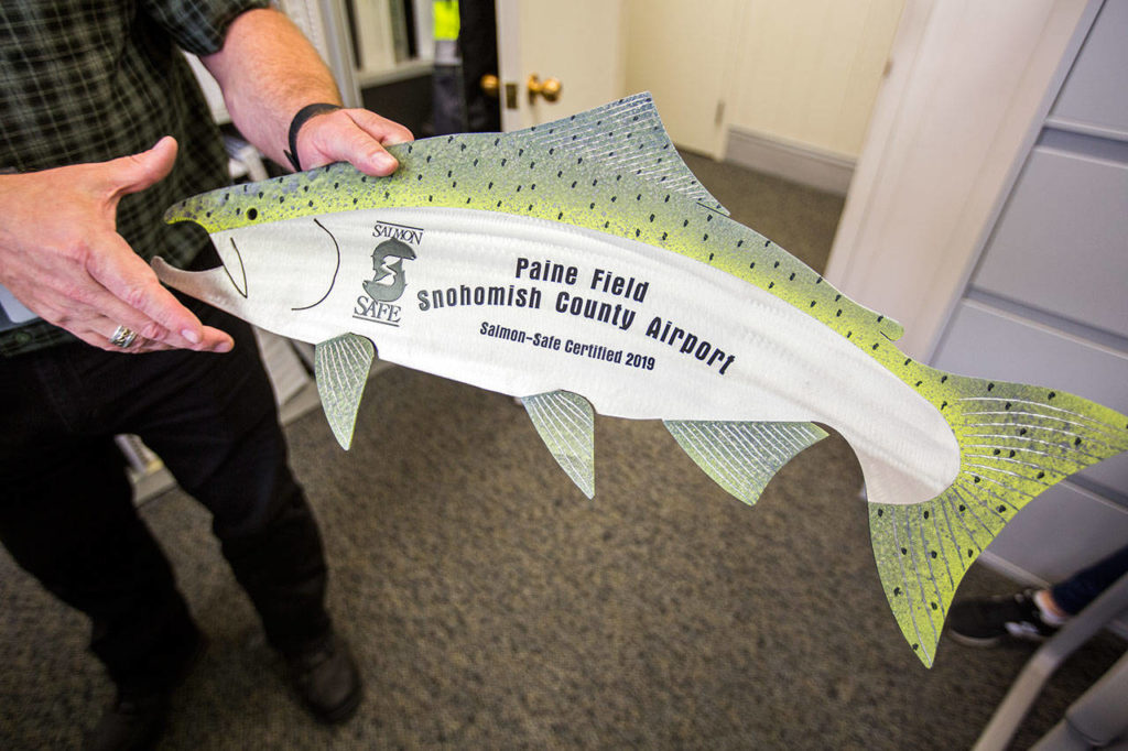Andrew Rardin opens a package that contains Paine Field’s Salmon Safe certification placard on Sept. 5 in Everett. (Olivia Vanni / The Herald)
