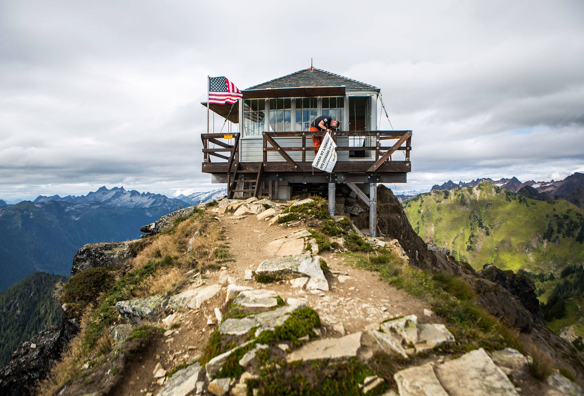 Don Sarver hangs up a Green Mountain Lookout steward banner on the exterior of the structure on Aug. 31. (Olivia Vanni / The Herald)