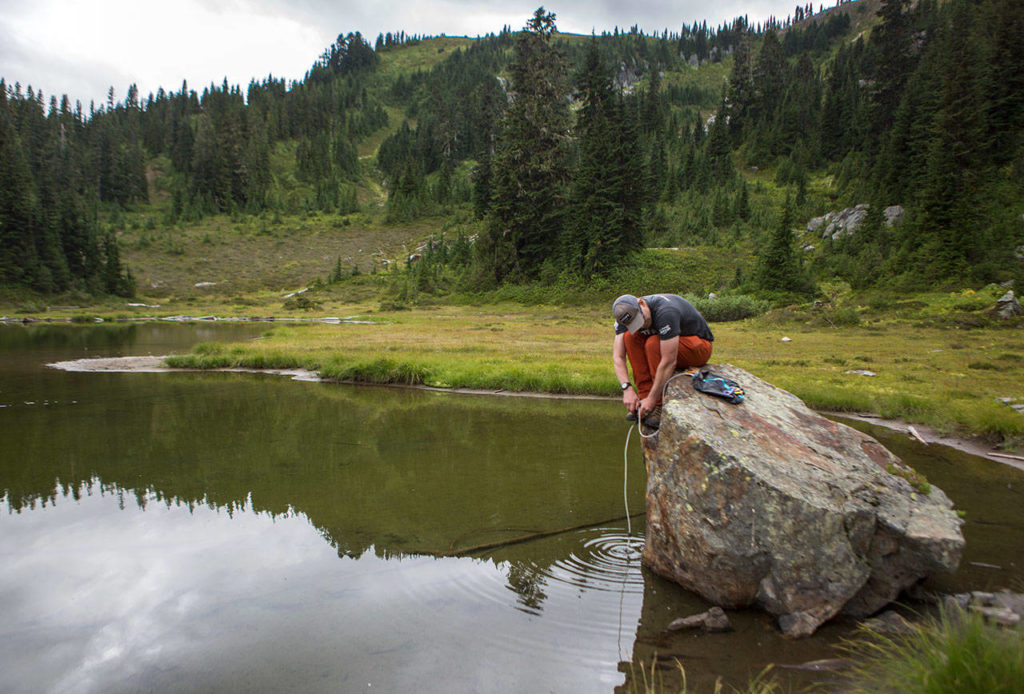 Don Sarver collects drinking water from a tarn below the peak through a hand-pumped filter. (Olivia Vanni / The Herald)
