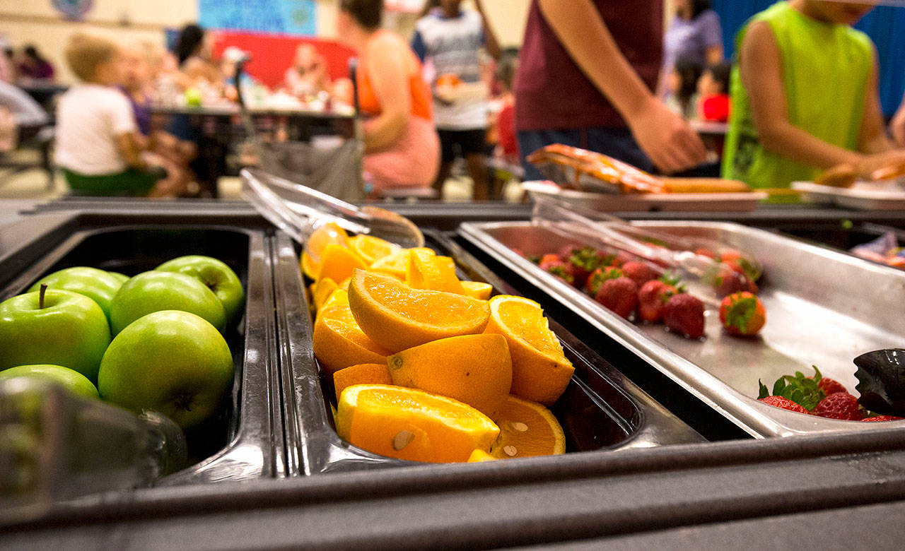 Families with children and teens eat at the Summer Free Lunch Program in the cafeteria at Sunnycrest Elementary in June 2018 in Lake Stevens. A report by the state Auditor’s Office recommends that schools allow more time for students to eat lunch and move recess prior to lunch, rather than after. (Andy Bronson / Herald file photo)