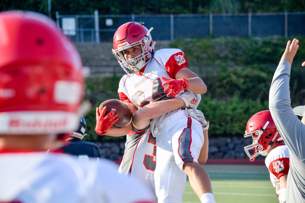 Junior defensive back Isaac Oretega is lifted up by his teammate after intercepting a Jackson pass in the second quarter on Friday at Everett Memorial Stadium. (Katie Webber / The Herald)
