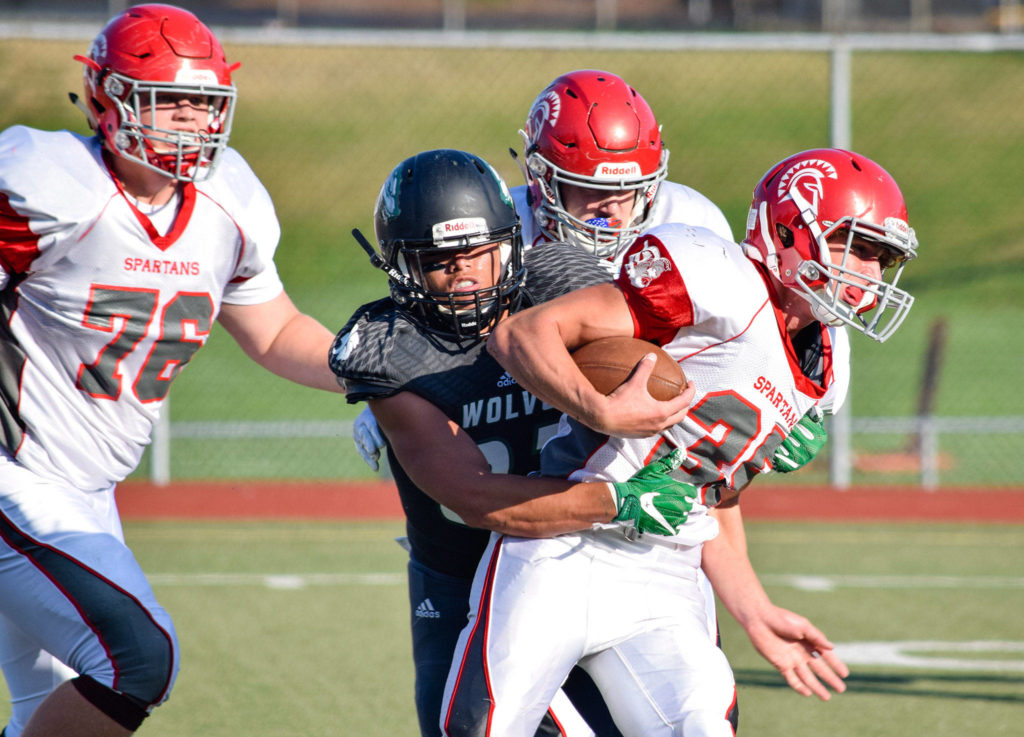 Junior running back Caden Carrigan runs with the ball while being tackeld by a Jackson defender on Friday at Everett Memorial Stadium. (Katie Webber / The Herald)
