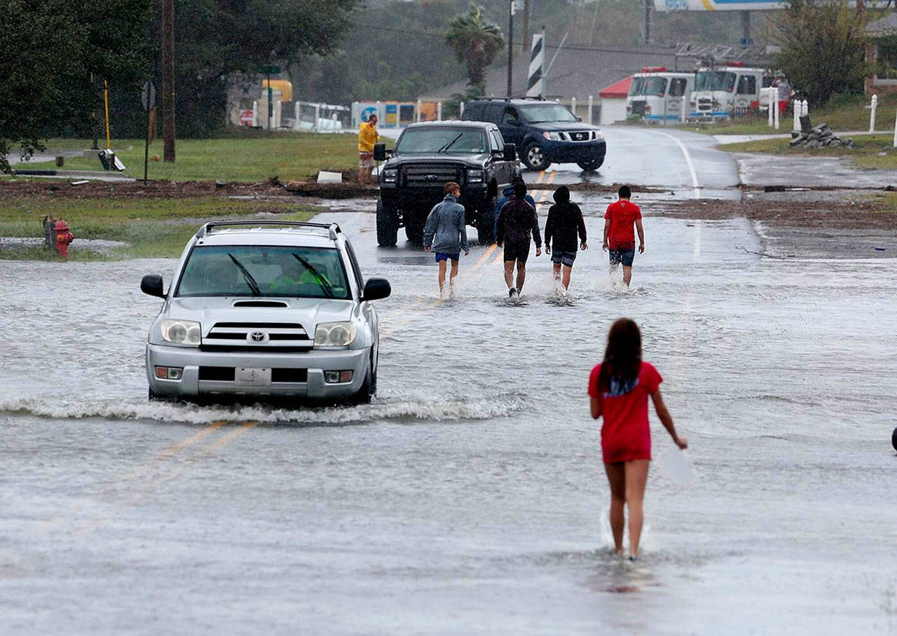 Residents walk and drive through the receding flood waters in Buxton, N.C., after Hurricane Dorian leaves Hatteras Island on Friday. (Steve Earley/The Virginian-Pilot via AP)
