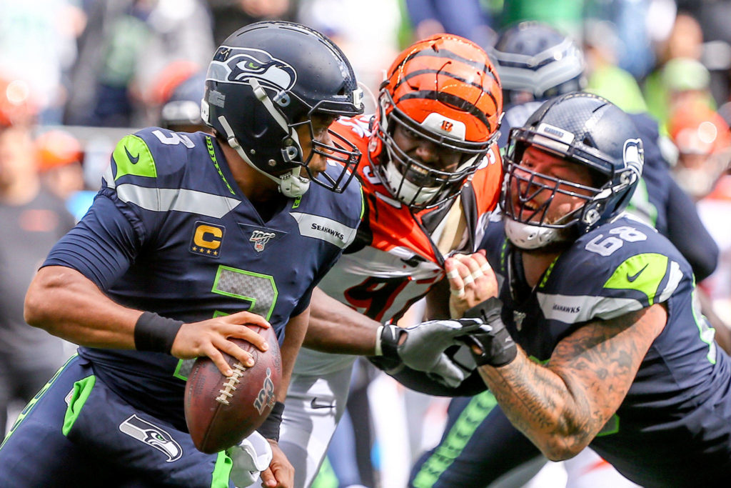Seattle’s Russell Wilson is chased out of the pocket by Cincinnati’s Geno Atkins with Justin Britt at CenturyLink Field Sunday afternoon in Seattle on September 8, 2019. The Seahawks won 21-20. (Kevin Clark / The Herald)
