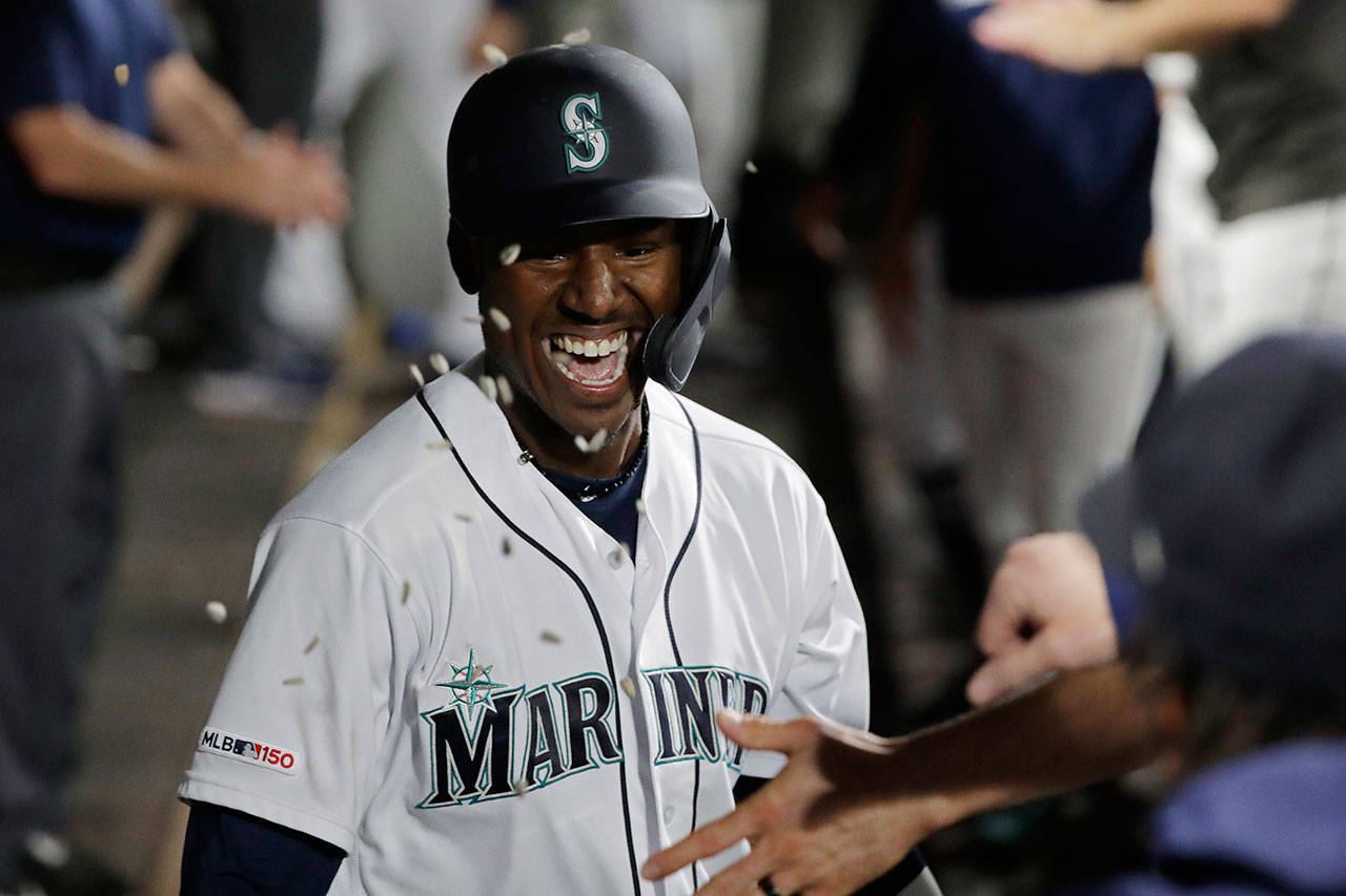 Sunflower seeds fly in the dugout as the Mariners’ Kyle Lewis is greeted after he hit a solo home run against the Reds during the fifth inning of a game Sept. 12, 2019, in Seattle. (AP Photo/Ted S. Warren)