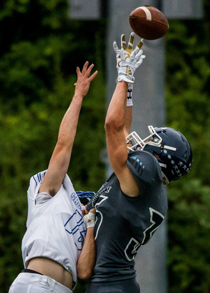 Meadowdale’s Mason Vaughn (right) reaches over Shorewood’s Dennis Buchheit for a pass during a game on Sept. 13, 2019, at Edmonds Stadium. (Olivia Vanni / The Herald)
