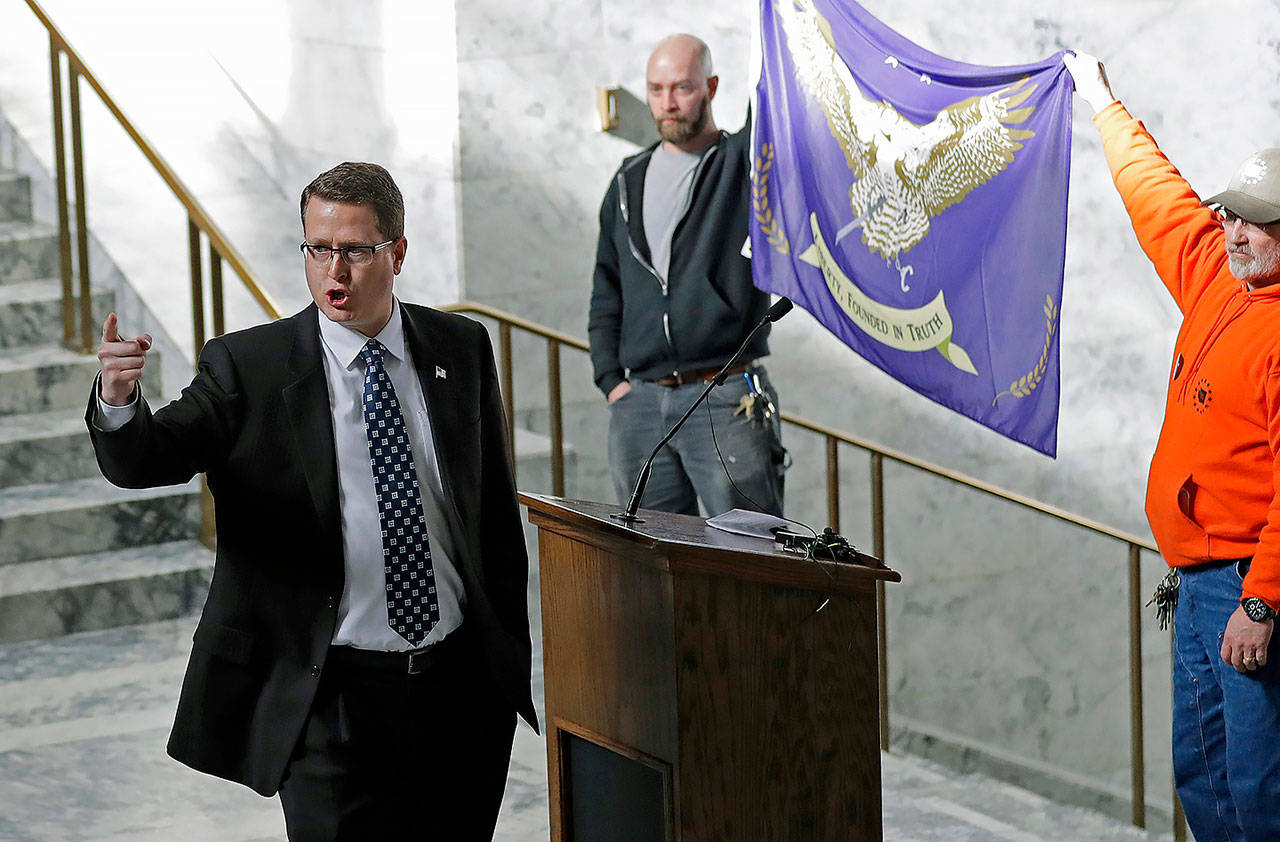 In this Feb. 15 photo, state Rep. Matt Shea, R-Spokane Valley, gestures as he gives a speech in front of the liberty state flag at the Capitol in Olympia, during a rally held by people advocating splitting Washington state into two separate states and questioning the legality of Washington’s I-1639 gun-control measure. (AP Photo/Ted S. Warren, File)