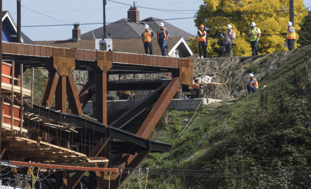 Crews watch as the east side of the Grand Avenue Park Bridge is lowered into place on Wednesday in Everett. (Andy Bronson / The Herald)
