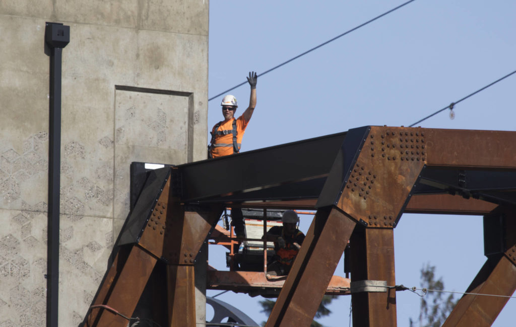 A worker waves to his mother as the Grand Avenue Park Bridge was lowered into place along Marine View Drive on Wednesday in Everett. (Andy Bronson / The Herald)
