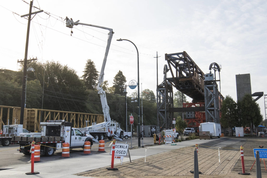 The $20 million Grand Avenue Park Bridge sits as two workers manage a power line before the bridge is rotated into place along Marine View Drive on Wednesday in Everett. (Andy Bronson / The Herald)
