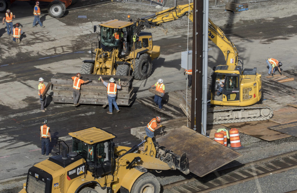 Worker lay down dunnage before the Grand Avenue Park Bridge can roll past a power pole and over railroad tracks on Wednesday in Everett. (Andy Bronson / The Herald)
