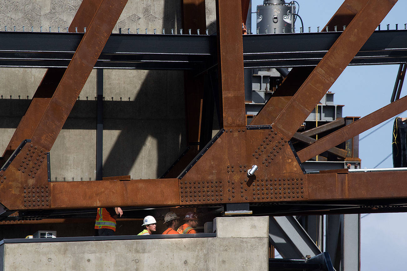 Workers watch from below as the $20 million Grand Avenue Park Bridge was slowly lowered into place above Marine View Drive on Wednesday, Sept. 25, 2019 in Everett, Wash. (Andy Bronson / The Herald)