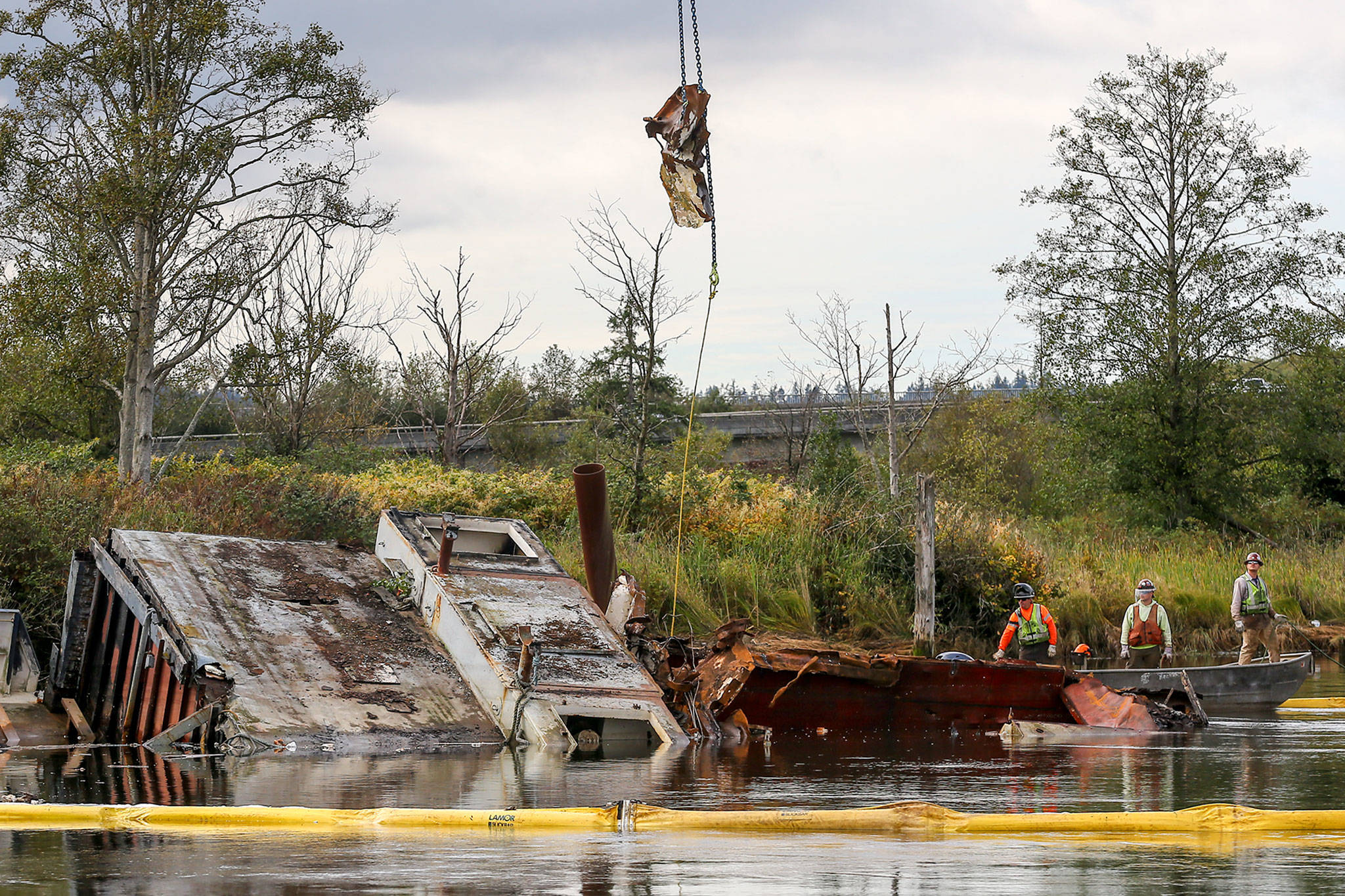 Crew members stand by as a crane moves metal away from the derelict boat Midas in the Snohomish River on Thursday. (Kevin Clark / The Herald)