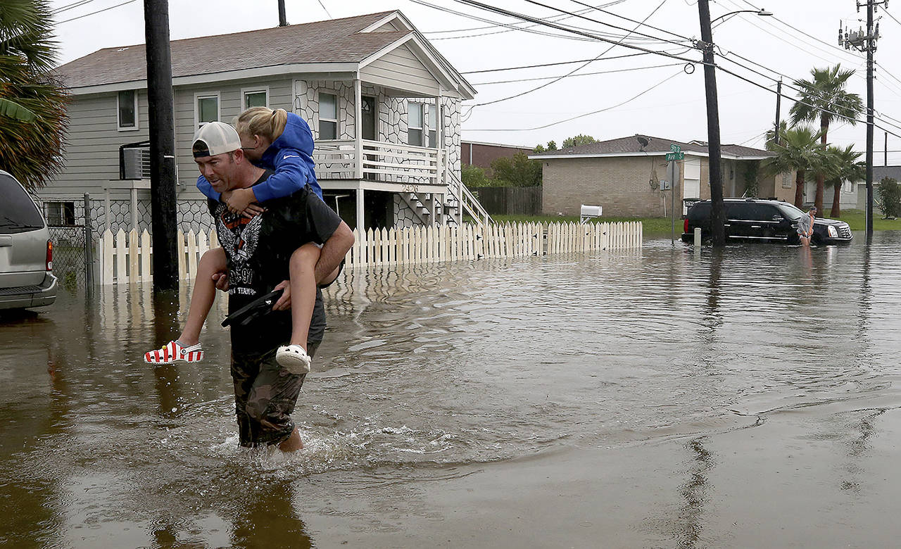 Terry Spencer carries his daughter, Trinity, through high water on 59th Street near Stewart Road in Galveston, Texas, on Wednesday as heavy rain from Tropical Depression Imelda caused street flooding on the island. (Jennifer Reynolds/The Galveston County Daily News via AP)