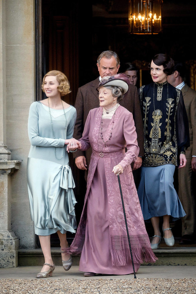Rushing out the front door to greet somebody important are Lady Edith Hexham (Laura Carmichael) The Dowager Countess of Grantham (Dame Maggie Smith), Lord Grantham (Hugh Bonneville), Irish son-in-law Tom Branson (Allen Leech) and Lady Grantham (Elizabeth McGovern).
