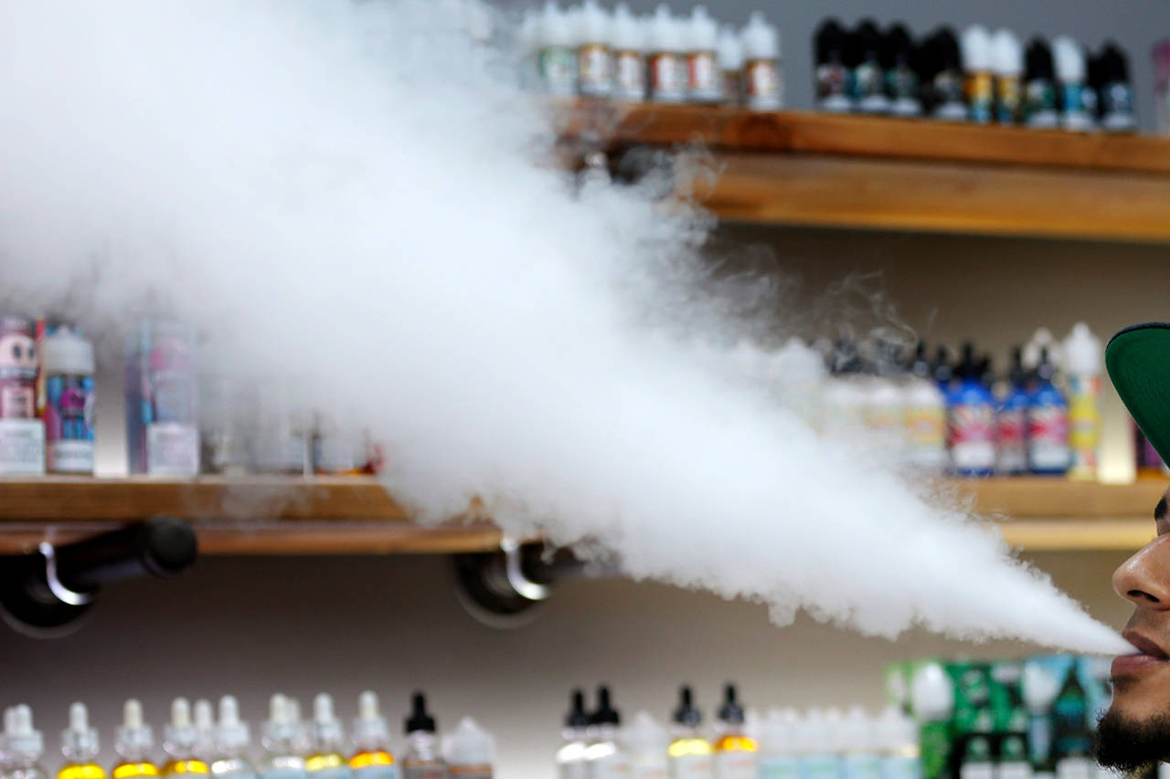 In this Sept. 3 photo, a salesman at a vape shop exhales while using an e-cigarette in Maine. (AP Photo/Robert F. Bukaty)