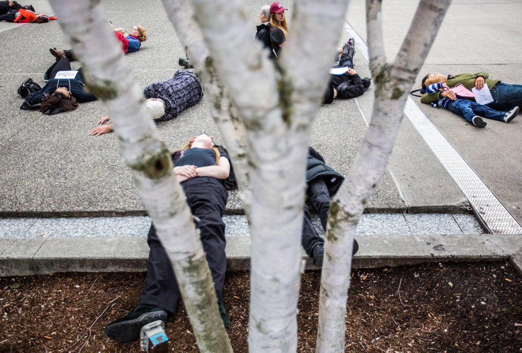 People participate in the “die-in” for climate action at the Snohomish County Campus Plaza on Friday in Everett. (Olivia Vanni / The Herald)
