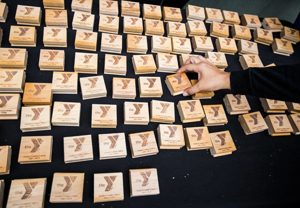 People grab wooden tokens made from leftover wood found in the original YMCA during the YMCA’s time capsule ceremony on Saturday, Sept. 21, 2019 in Everett, Wash. (Olivia Vanni / The Herald)

