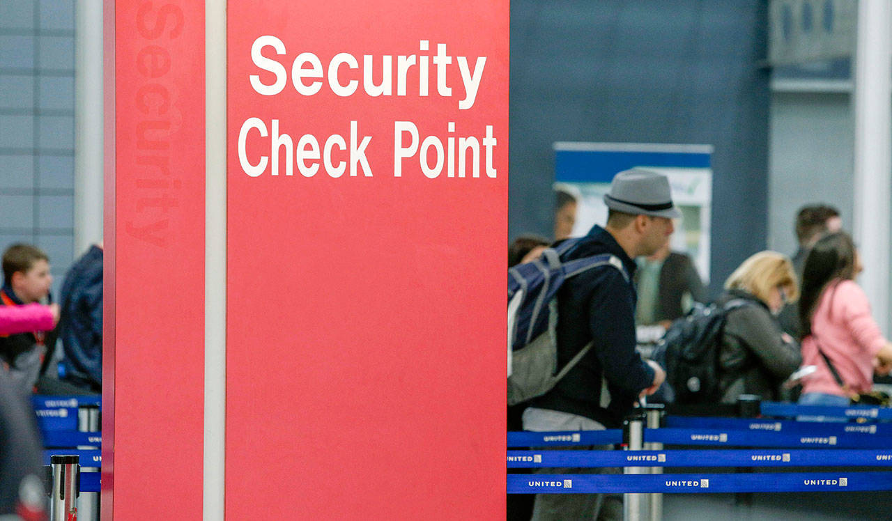 Passengers check into their flights near a security checkpoint sign at O’Hare International Airport in Chicago on March 22, 2016.. (AP Photo/Teresa Crawford, File)