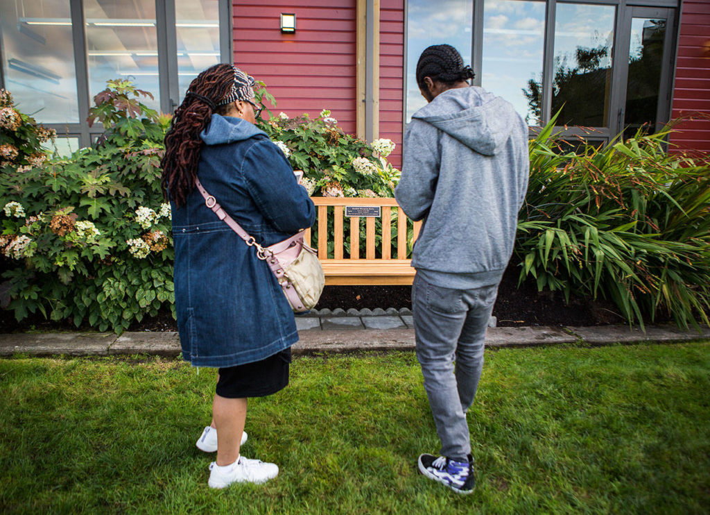 Jennifer Lowe, left, and Kelyn Lowe-Key, right, pause to take photos of Ezekiel’s bench Saturday at the Rosehill Community Center in Mukilteo. (Olivia Vanni / The Herald)
