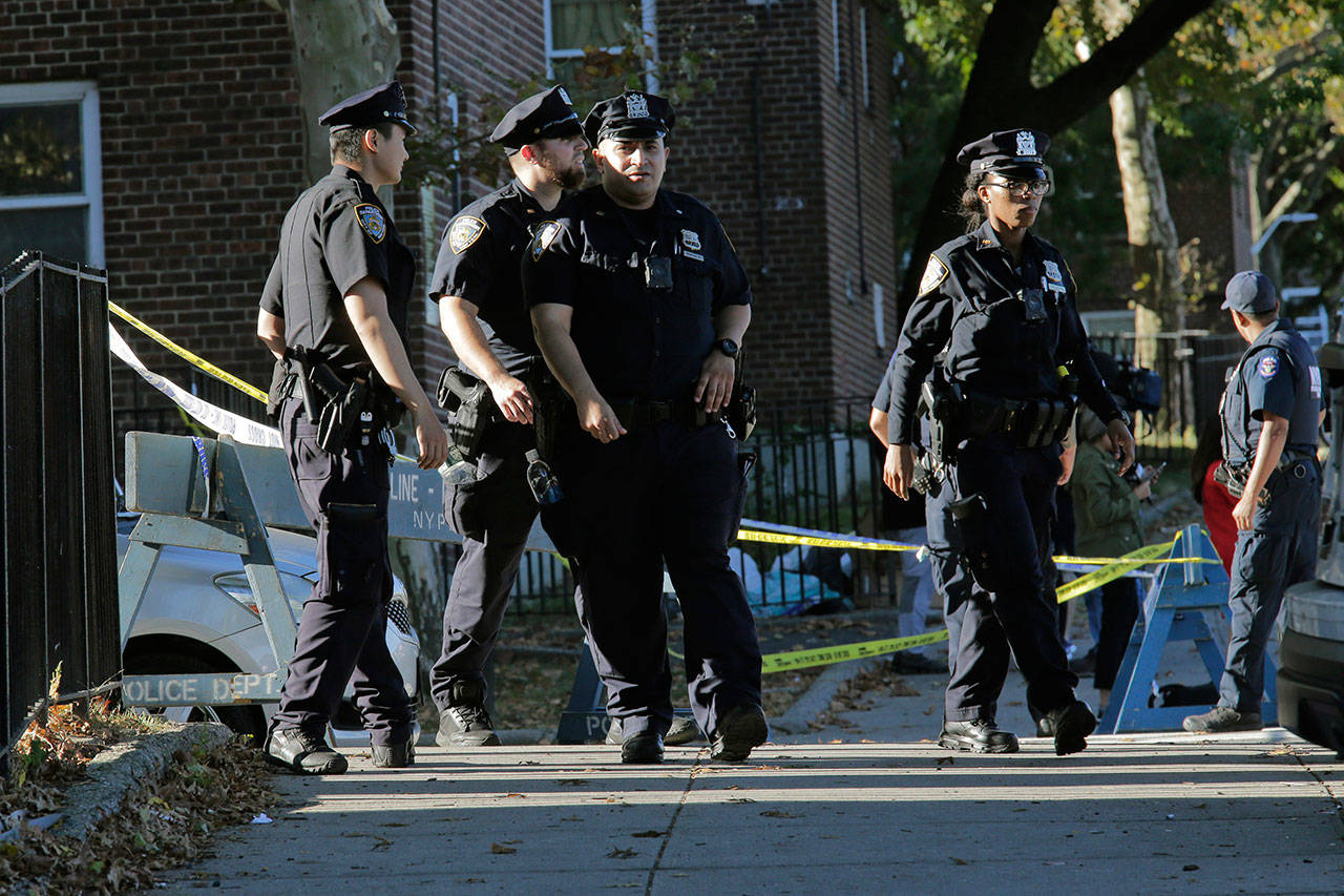 Emergency personnel walk near the scene of a fatal shooting of a New York City police officer Sunday in the Bronx borough of New York. (AP Photo/Seth Wenig)