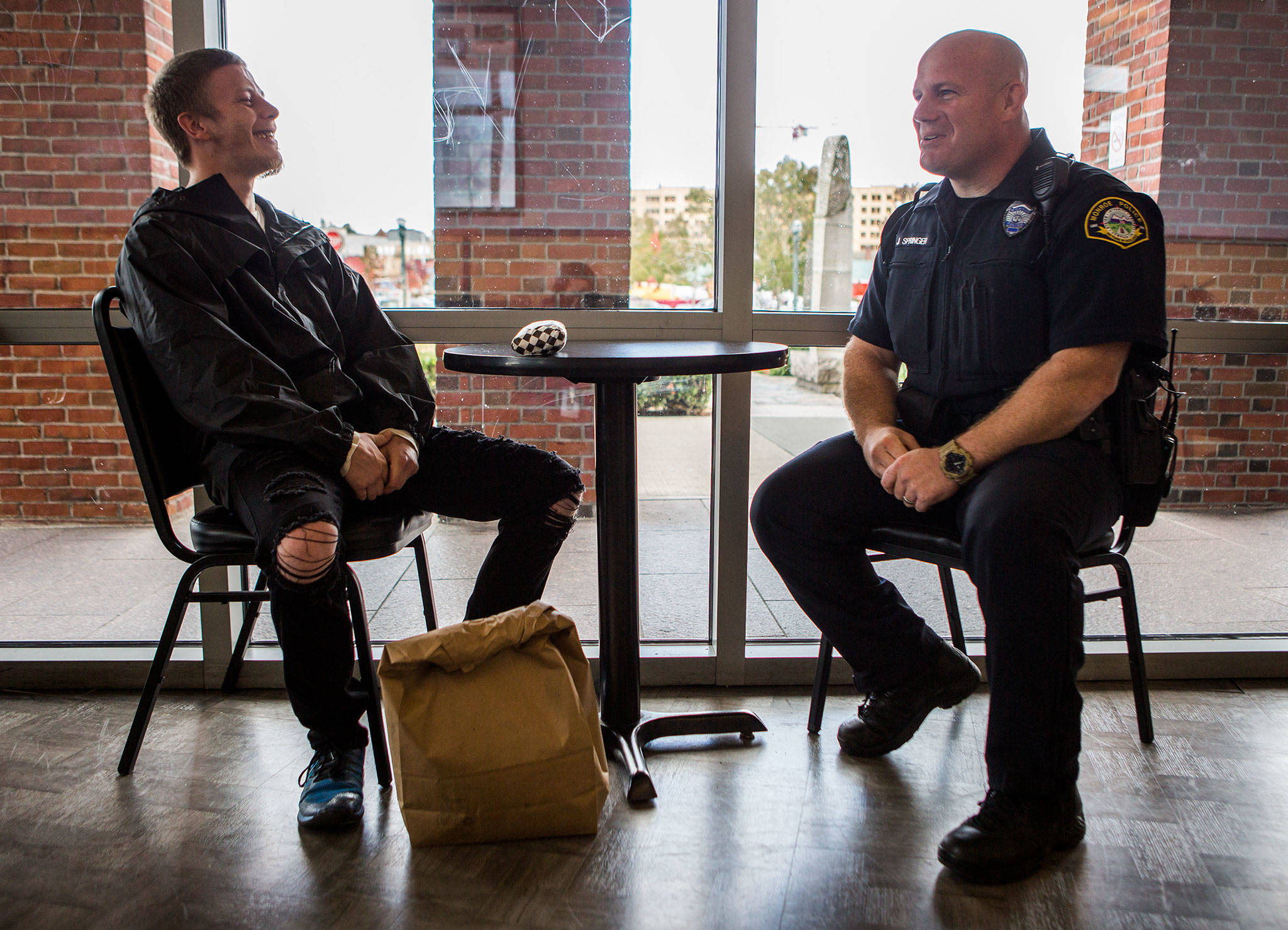 Oliver Gerds (left) chats with Monroe Police Officer Justin Springer while they wait for Gerds’ bus to Spokane to arrive on Thursday in Everett. Gerds was homeless when he was picked up in Monroe by officers and was released from jail Thursday into Springer’s custody to be transported to a treatment center in Spokane. (Olivia Vanni / The Herald)
